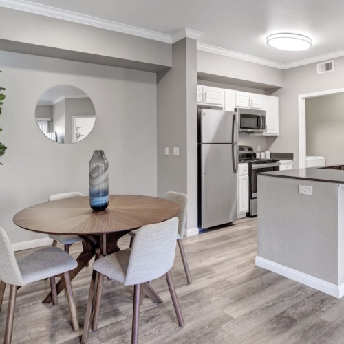 a kitchen with a table, chairs and a plant