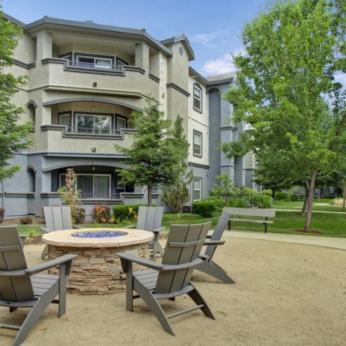 a fire pit with chairs in front of a building